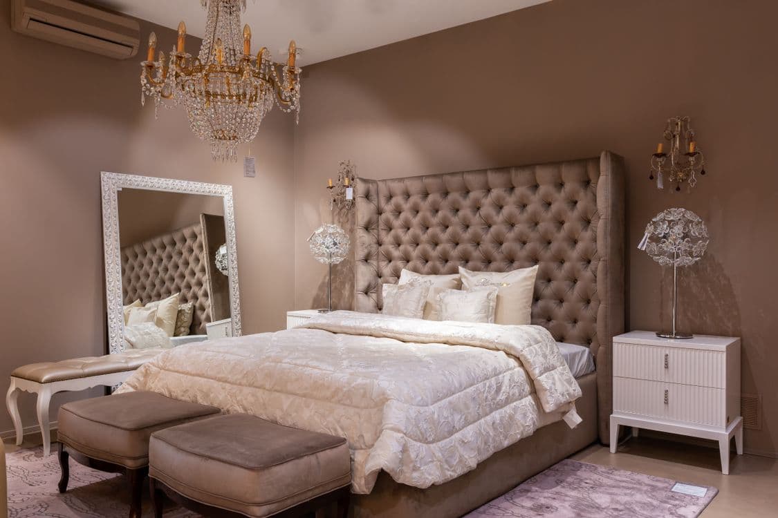 Luxurious bedroom with tufted headboard near mirror