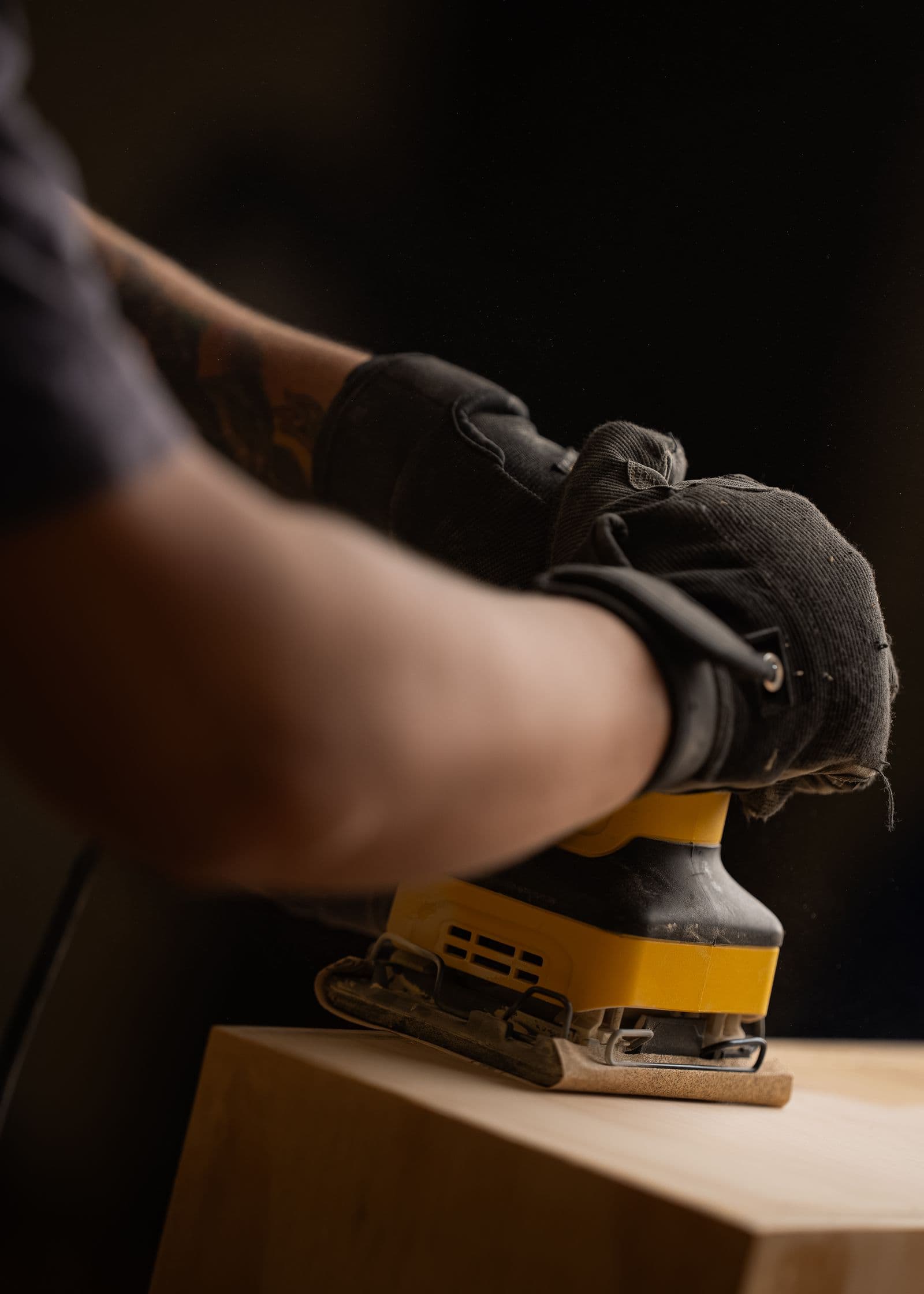 Close-up of carpenter sanding wood in workshop
